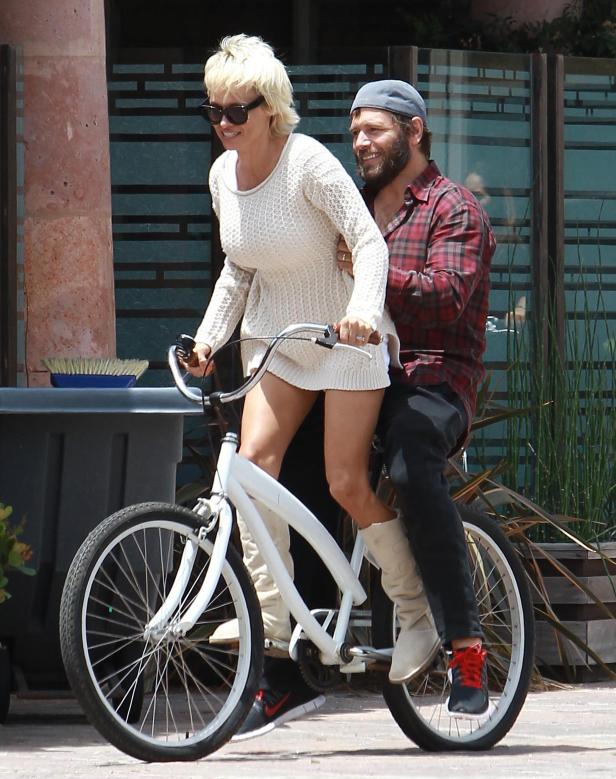 Eine Frau und ein Mann fahren zusammen auf einem weißen Fahrrad.