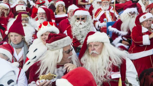 Eine große Gruppe von Menschen, die als Weihnachtsmänner verkleidet sind, sitzen zusammen.