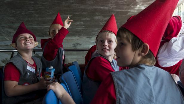 Eine Gruppe Kinder mit roten Zipfelmützen sitzt in einem Bus.