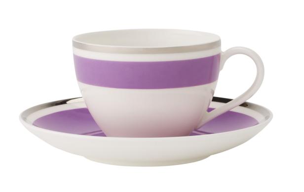 Eine weiße Teetasse mit lila Streifen steht auf einer Untertasse.