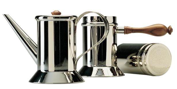Eine Kaffeekanne und Zubehör aus glänzendem Metall und Holz stehen auf einem Tisch.