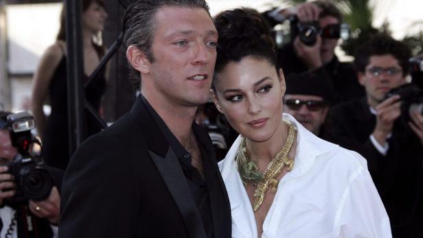 Monica Bellucci und Vincent Cassel posieren auf einem roten Teppich, umgeben von Fotografen.