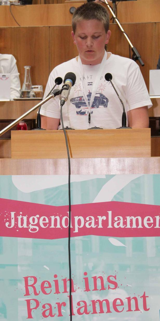 Ein Jugendlicher steht am Rednerpult des Jugendparlaments.