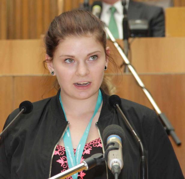 Eine junge Frau spricht am Rednerpult in ein Mikrofon.