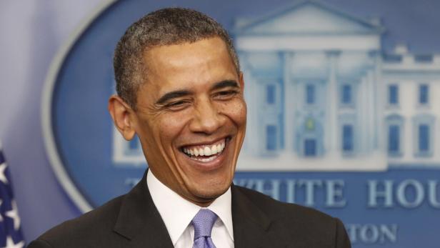 Ein lachender Barack Obama vor einem Hintergrund des Weißen Hauses.
