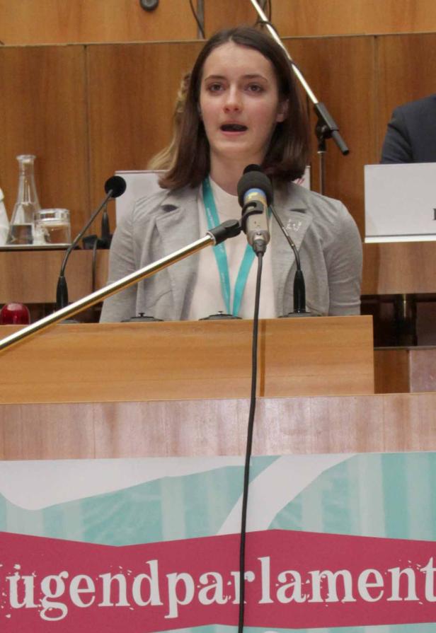 Eine junge Frau spricht am Rednerpult während einer Sitzung des Jugendparlaments.