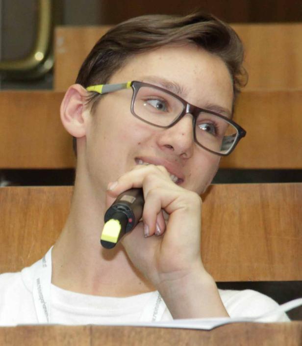 Ein junger Mann mit Brille hält ein Mikrofon vor seinem Mund.