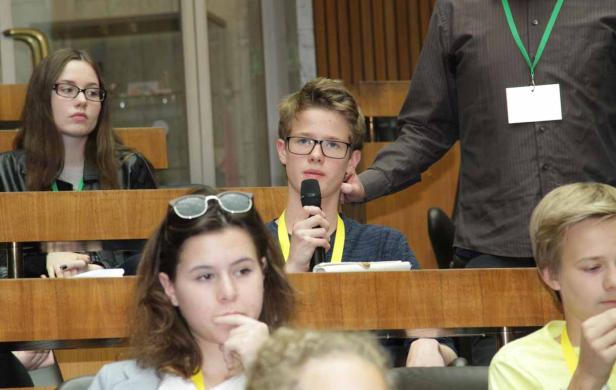 Ein junger Mann spricht bei einer Veranstaltung in ein Mikrofon.