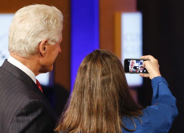 Eine Frau fotografiert Bill Clinton mit ihrem Smartphone.