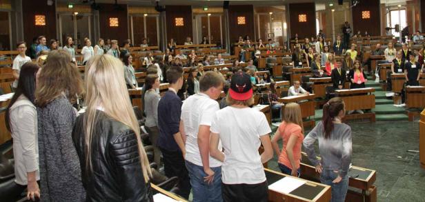 Eine Gruppe junger Leute steht im österreichischen Parlament während einer simulierten Sitzung.