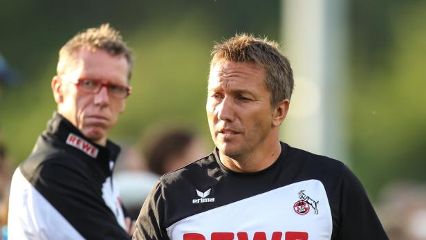 Zwei Männer, vermutlich Trainer des 1. FC Köln, stehen auf dem Trainingsplatz.