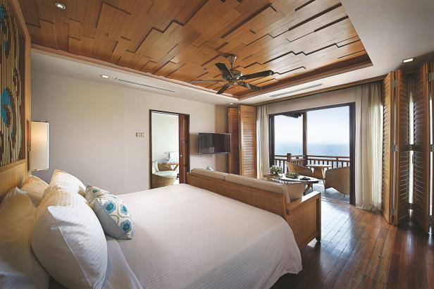 Ein Schlafzimmer mit Holzboden und einem Balkon mit Blick auf das Meer.