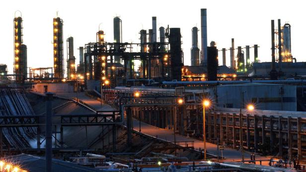 Eine große Industrieanlage mit vielen Rohren und Türmen bei Dämmerung.