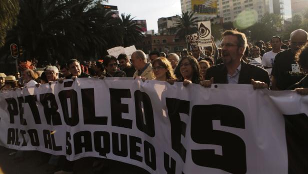 Eine Menschenmenge demonstriert mit einem Banner, auf dem „Petróleo es alto al saqueo“ steht.
