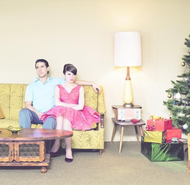 Ein Paar sitzt verstimmt auf einem Sofa neben einem Weihnachtsbaum.