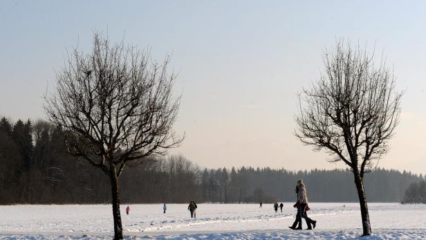 Winterliche Landschaft mit Menschen, die über eine schneebedeckte Fläche laufen.