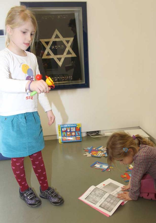Zwei Mädchen spielen mit einem Puzzle mit jüdischen Symbolen in einem Raum.