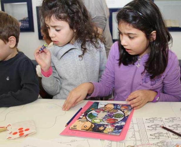 Zwei Mädchen sitzen an einem Tisch und betrachten ein buntes Bild mit Lebensmitteln.
