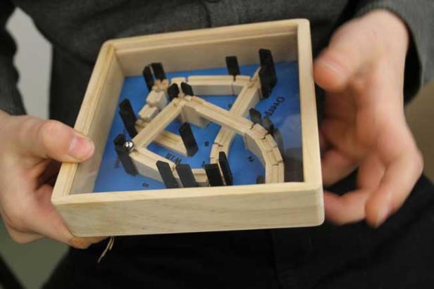 Eine Person hält ein Geschicklichkeitsspiel mit einer Kugel in den Händen.