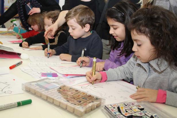 Eine Gruppe Kinder sitzt an einem Tisch und malt mit Stiften auf Papier.