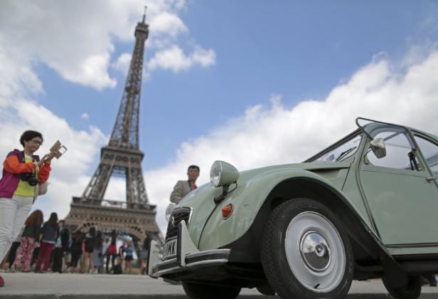 Ein grüner Citroën 2CV vor dem Eiffelturm in Paris.