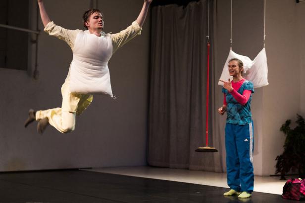 Ein Mann springt mit einem Kissenkostüm in die Luft, während eine Frau daneben steht und zusieht.