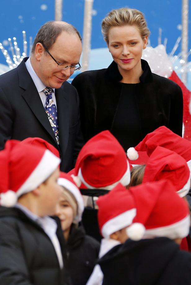 Fürst Albert II. und Fürstin Charlène von Monaco mit Kindern mit Weihnachtsmützen.
