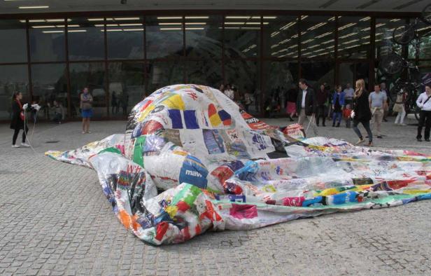 Eine große, bunte Skulptur aus recycelten Materialien steht im Freien.