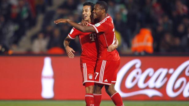Zwei Fußballspieler des FC Bayern München umarmen sich auf dem Spielfeld.