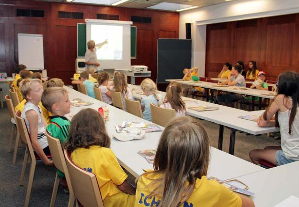 Ein Lehrer präsentiert eine Lektion vor einer Gruppe von Kindern in einem Klassenzimmer.