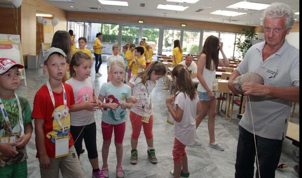 Eine Gruppe Kinder steht in einem Raum, während ein Mann mit einer Puppe interagiert.