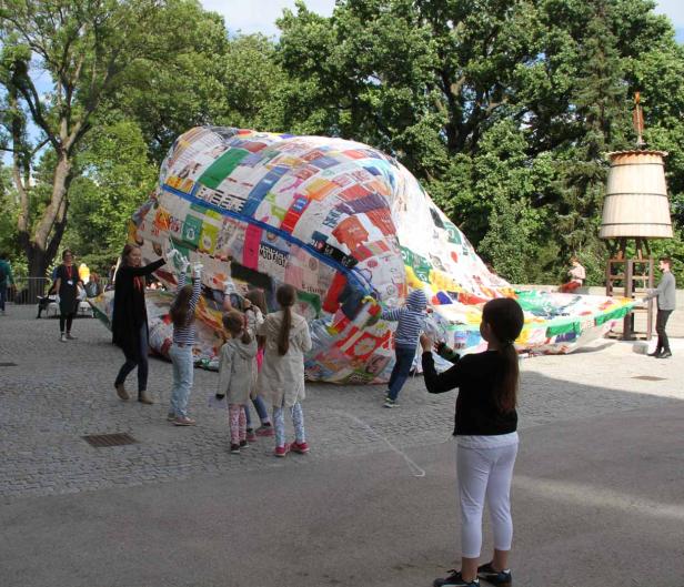 Kinder spielen mit einem großen, bunten Ballon im Freien.