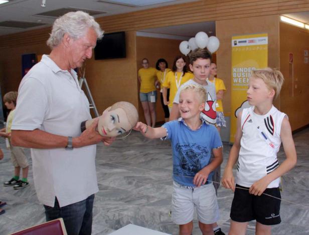 Ein Mann hält einen Übungskopf, während Kinder zusehen.