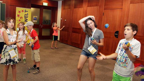 Eine Gruppe von Kindern und Jugendlichen jongliert mit Bällen in einem Raum.