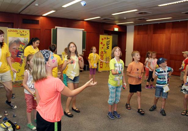 Eine Gruppe Kinder übt Jonglieren in einem Raum mit Zirkusdekorationen.