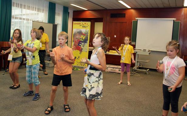 Eine Gruppe Kinder übt sich im Jonglieren mit Bällen in einem Raum.