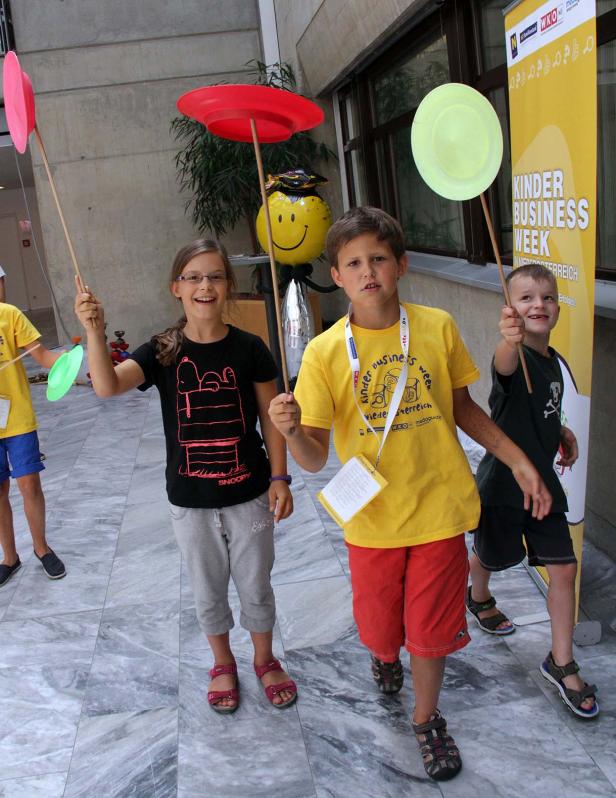 Kinder balancieren Teller auf Stäben während der Kinder Business Week.