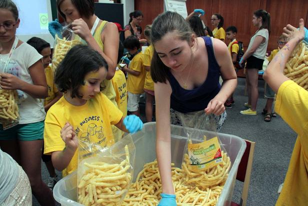 Kinder füllen Tüten mit Mais-Stangerl.