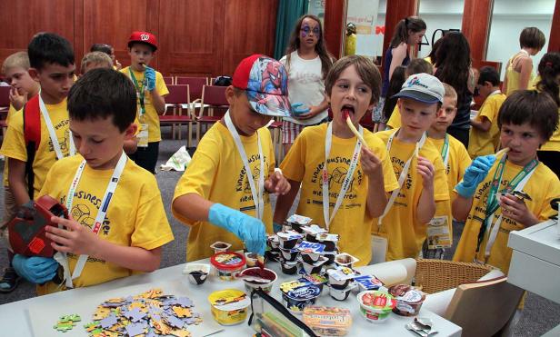 Eine Gruppe Kinder in gelben T-Shirts beschäftigt sich mit Essen und Puzzlespielen.