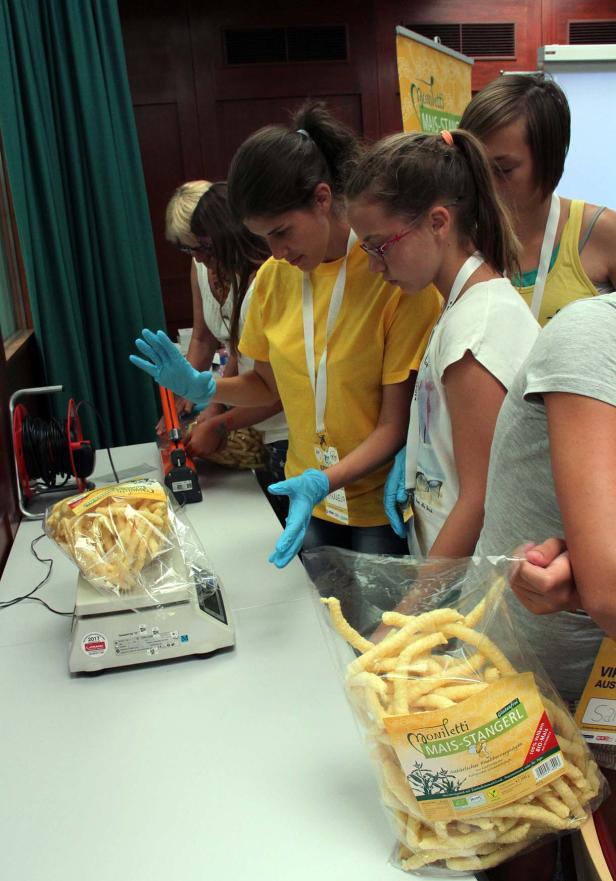 Mehrere Personen verpacken „Moniletti Mais-Stangerl“ in Plastiktüten.