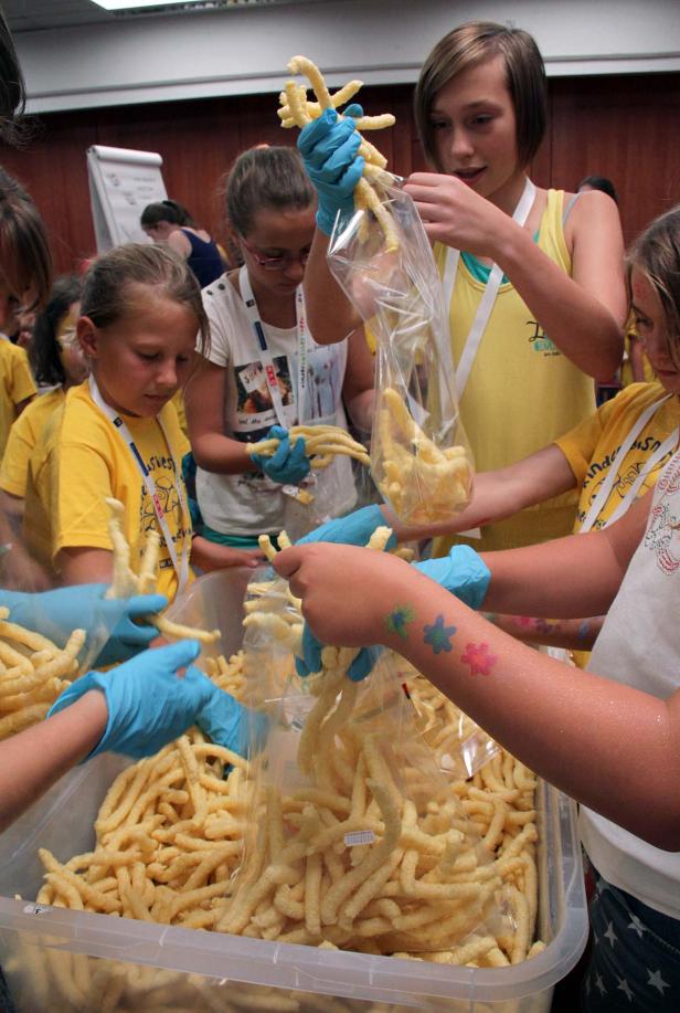 Kinder verpacken mit Handschuhen Kartoffelstäbchen in Plastiktüten.