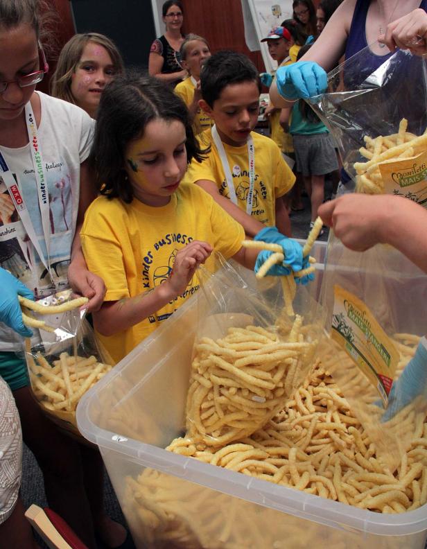 Kinder füllen Maisstangen in Tüten ab.