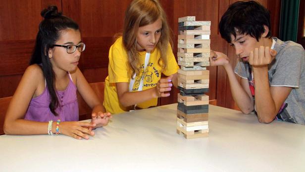 Drei Kinder spielen ein Geschicklichkeitsspiel mit Holzklötzen.
