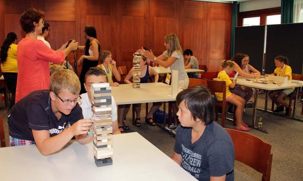 Kinder spielen in einem Raum mit einem Holzklotz-Turm.