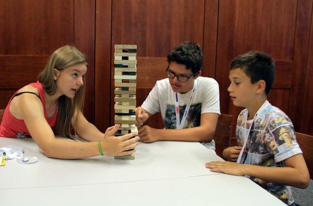 Drei Jugendliche spielen zusammen ein Geschicklichkeitsspiel mit Holzklötzen.