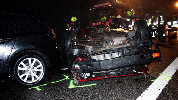 Ein Autounfall mit Feuerwehrleuten und Polizisten am Unfallort bei Nacht.