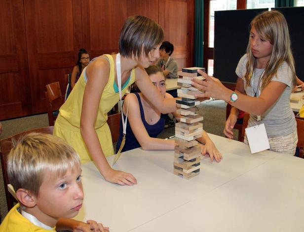 Mehrere Kinder spielen zusammen ein Geschicklichkeitsspiel mit Holzklötzen.
