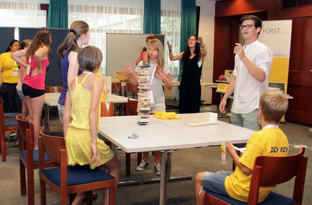 Eine Gruppe von Jugendlichen spielt mit einem Jenga-Turm in einem Raum.