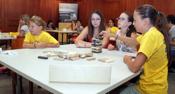 Eine Gruppe Kinder spielt mit Holzbausteinen an einem Tisch.