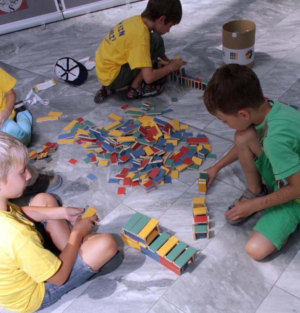 Mehrere Kinder spielen mit bunten Holzbausteinen auf einem Boden.